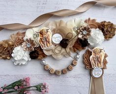 a bunch of flowers and buttons on a white table with some brown ribbon around it