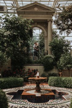 an engaged couple standing on the balcony of a building surrounded by greenery and flowers