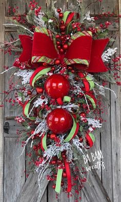 a christmas wreath with red apples and holly on the front door, hanging from a wooden door