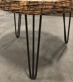 a wooden table with hairpin legs on concrete flooring and walls in the background