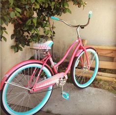 a pink and blue bicycle parked next to a tree