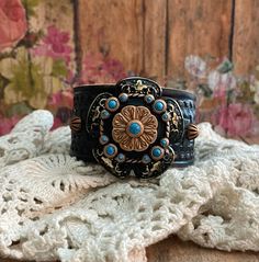 Southwestern Turquoise Copper & Black Flower Concho Leather Cuff Bracelet> Leather Wristband. Flower Jewelry. Southwest Jewelry. Rustic Boho Adjustable Western Cuff Bracelet For Festivals, Adjustable Western Style Cuff Bracelet For Festivals, Adjustable Western Style Festival Cuff Bracelet, Western Style Adjustable Cuff Bracelet For Festivals, Adjustable Concho Cuff Bracelet For Festival, Black Hand Tooled Bohemian Jewelry, Black Hand-tooled Bohemian Jewelry, Adjustable Western Cuff Bracelet With Patina, Black Bohemian Hand-tooled Jewelry