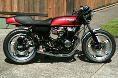 a red and black motorcycle parked in front of a wooden fence