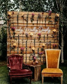 an old chair sitting next to a wooden wall with roses on it and the words truly married happily written in cursive writing