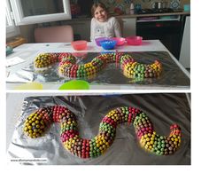 a child sitting at a table in front of a cake made to look like a snake