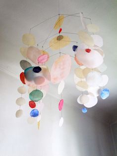 a mobile made out of paper plates hanging from the ceiling in a room with white walls