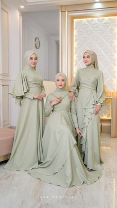 three women in long dresses standing next to each other on a white tiled room floor