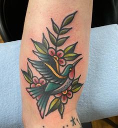 a bird with flowers and leaves on it's leg is shown in this tattoo design