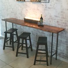 three stools and a table in front of a brick wall with lights on it