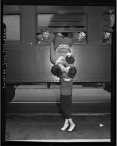 two people are standing in front of a train and one person is holding the other