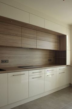 an empty kitchen with wooden cabinets and white cupboards, in the middle of a large open floor plan