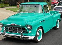 an old green truck parked in a parking lot