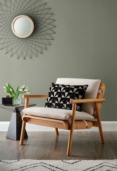 a wooden chair sitting in front of a wall with a mirror on top of it