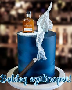 a blue birthday cake with a bottle of whiskey and tissue paper on top that is wrapped in plastic