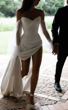 a woman in a white dress is holding the hand of a man