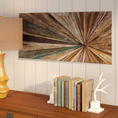 a lamp and some books on a wooden table next to a wall with white paneling