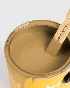 a yellow paint can with a wooden spatula sticking out of it's side