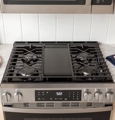 a stainless steel stove top oven in a kitchen with white tile backsplashing