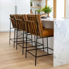 a kitchen with marble counter tops and barstools in front of an island that has four chairs on it