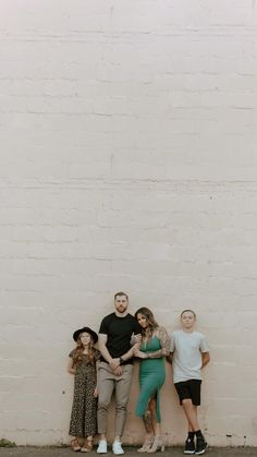 four people standing in front of a white brick wall with their arms around each other