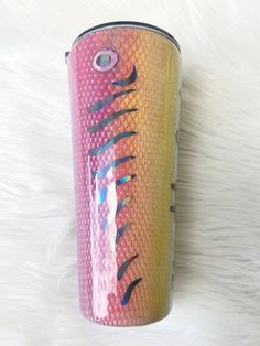 a pink and yellow can with black writing on it sitting on a white fur covered surface