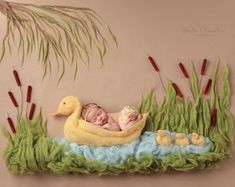 a baby is sleeping in a yellow ducky on the grass next to reeds