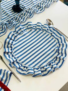 blue and white striped placemats with silverware on them sitting on a table