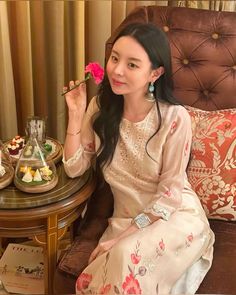 a woman sitting in a chair holding a flower