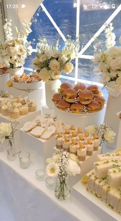 a table topped with lots of different types of cakes and desserts next to flowers