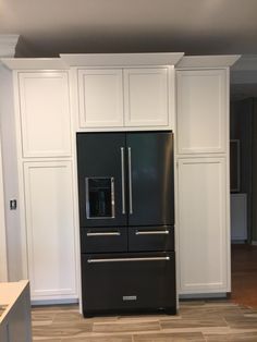 a black refrigerator freezer sitting inside of a kitchen next to white cabinets and drawers