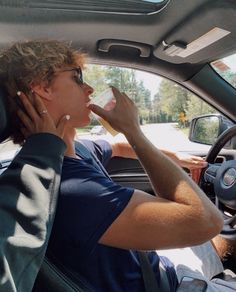 a woman sitting in the driver's seat of a car drinking from a cup