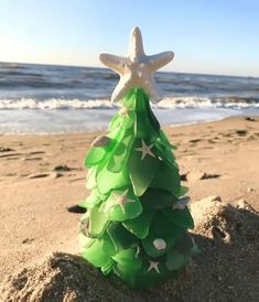 a green christmas tree on the beach with starfish