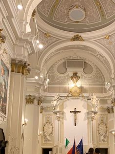 the interior of a church with people standing in front of it and flags hanging from the ceiling