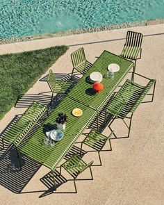 an aerial view of a table and chairs on the grass next to a swimming pool