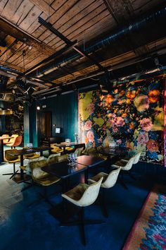 a dining room filled with lots of tables and chairs next to a wall covered in flowers