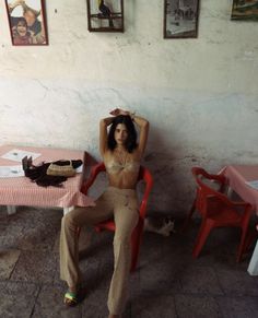 a woman sitting on top of a red chair next to a table