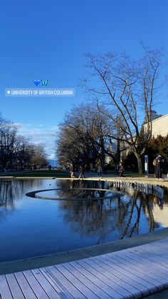 the reflection of trees in the water is very clear and blue with people walking around it