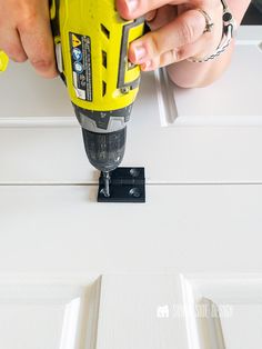 a person using a drill to attach the bottom part of a door