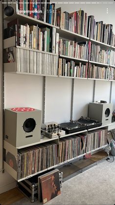 a record player is sitting on top of a shelf full of records and cds in front of a bookshelf