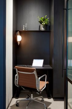 an office with a desk and chair in the corner next to a wall mounted shelf