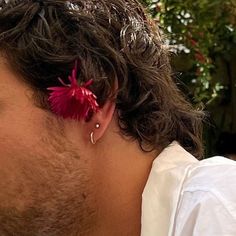 a close up of a person with a flower in their ear