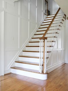 a white staircase with wooden handrails in a house