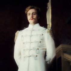 a man in white uniform standing next to a flag