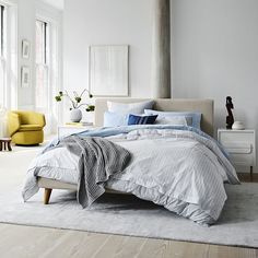 a bedroom with white walls and wood flooring has a large bed in the center