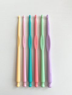 four different colored toothbrushes lined up in a row on a white surface,