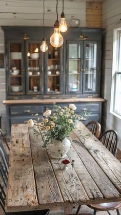 a wooden table sitting in the middle of a kitchen next to a vase with flowers on it