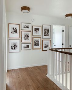 a hallway with pictures hanging on the wall and wooden flooring in front of it