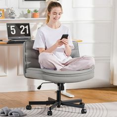 a woman sitting in an office chair on her cell phone and looking at the screen