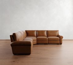 a brown leather couch sitting on top of a wooden floor next to a white wall