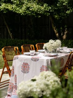 the table is set with white flowers and plates